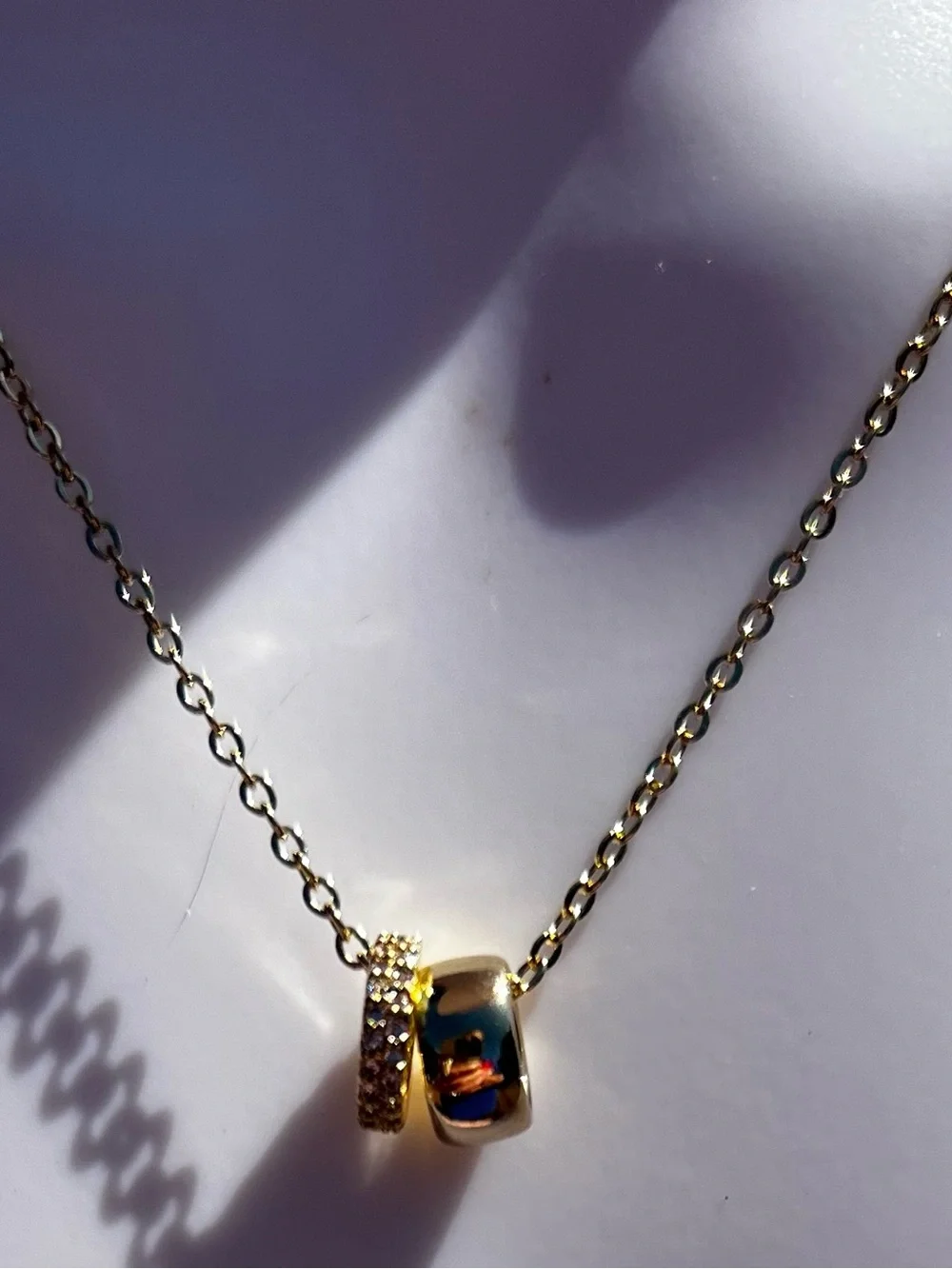 Elegant gold-tone pendant necklace featuring a pavé double ring design. NWT.